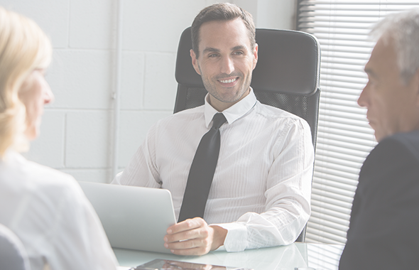 Employee holding tablet smiles at two clients across a desk