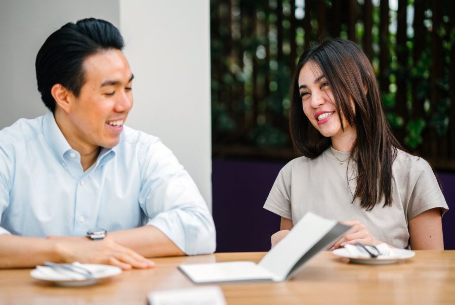 Two employees sit outside smiling