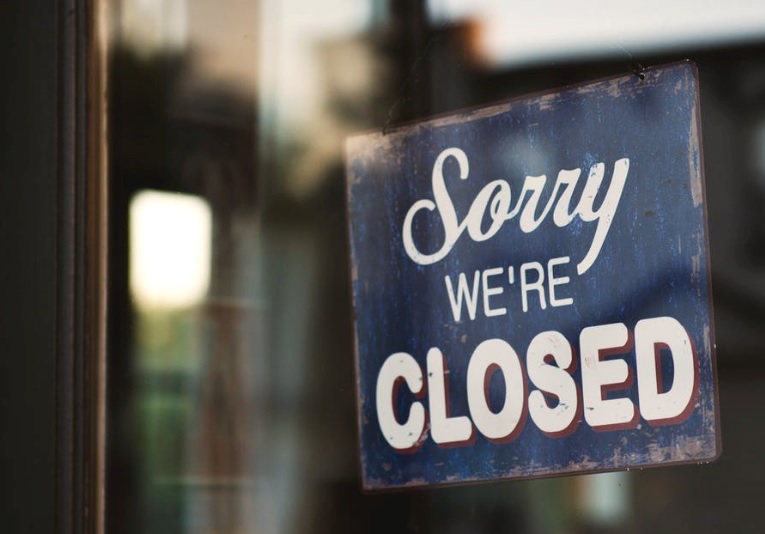 Glass shop door with weathered blue sorry were closed sign in white text