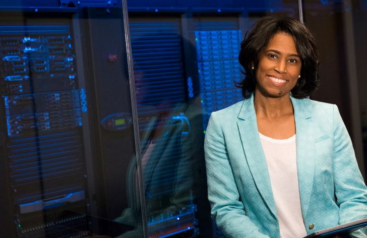 Employee stands with back to blue lit glass fronted server cabinets 